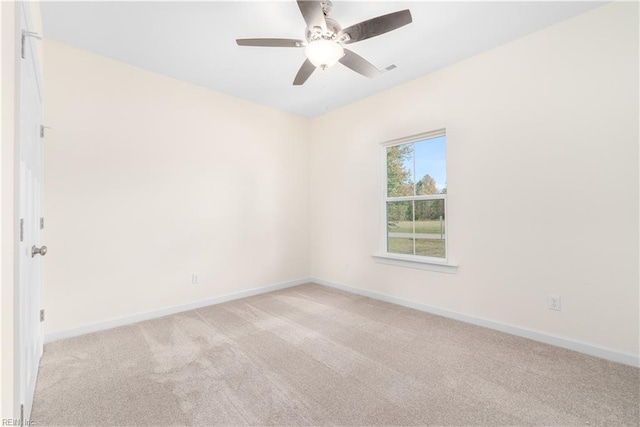 spare room with baseboards, ceiling fan, and light colored carpet