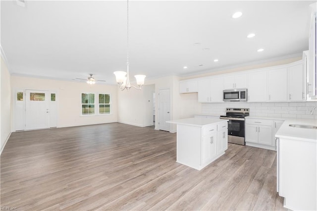 kitchen featuring a center island, stainless steel appliances, light wood-style flooring, decorative backsplash, and a sink