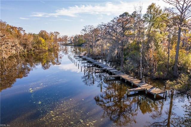 view of dock with a water view and a wooded view