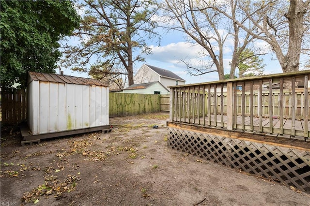 view of yard with an outbuilding, a shed, a fenced backyard, and a wooden deck