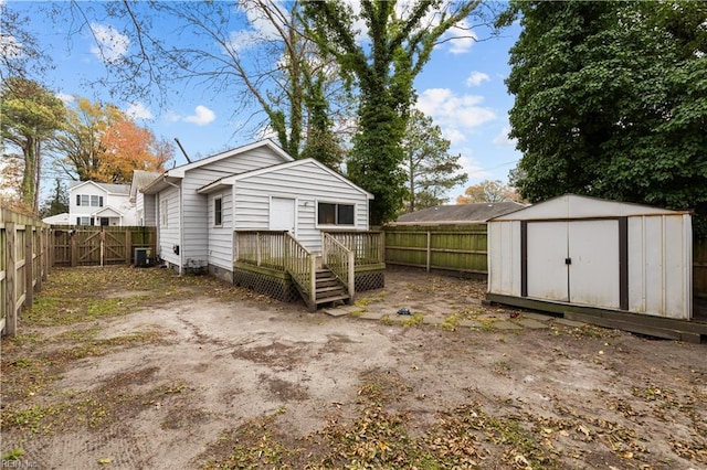 rear view of property with a fenced backyard, a storage unit, cooling unit, and an outbuilding