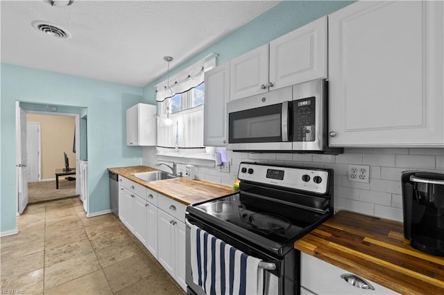 kitchen featuring stainless steel appliances, a sink, white cabinetry, wooden counters, and backsplash