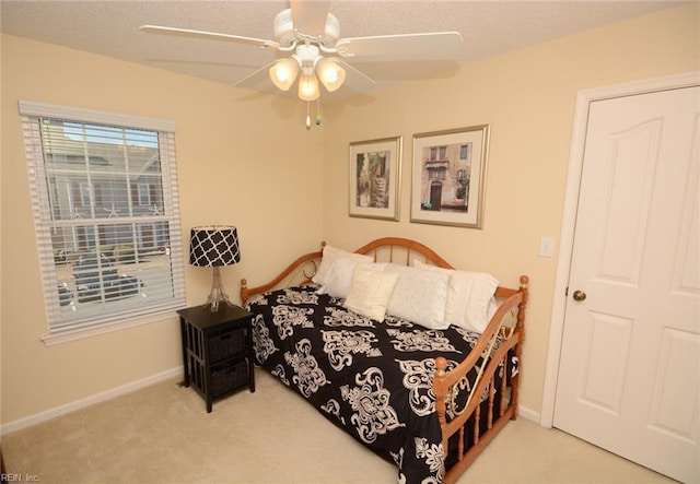 carpeted bedroom with ceiling fan and baseboards