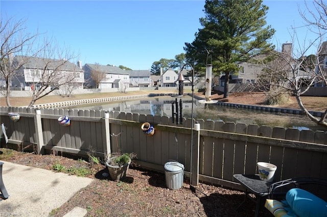 view of yard featuring a water view, a fenced backyard, and a residential view