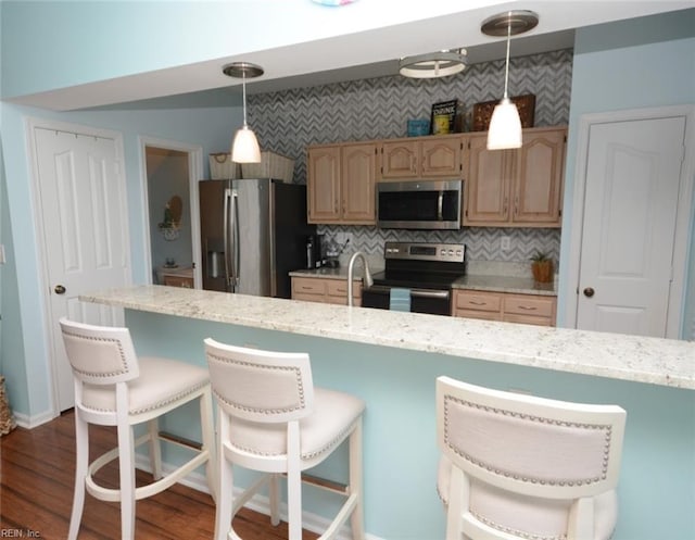 kitchen featuring tasteful backsplash, appliances with stainless steel finishes, a kitchen breakfast bar, dark wood-style flooring, and light brown cabinets