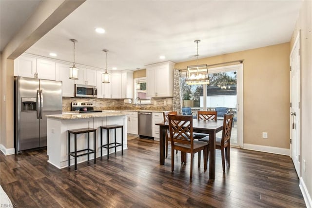 dining room with dark wood-style floors, baseboards, a wealth of natural light, and recessed lighting