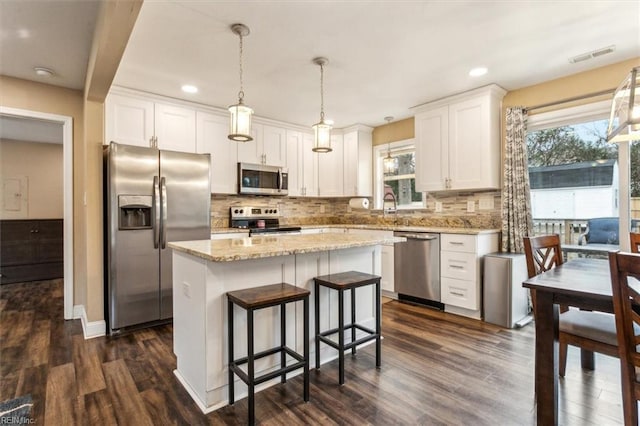 kitchen featuring stainless steel appliances, visible vents, dark wood-type flooring, white cabinetry, and a kitchen island