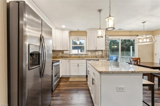 kitchen featuring a breakfast bar area, stainless steel appliances, dark wood-style flooring, a sink, and a center island