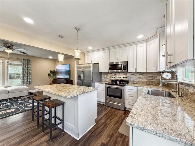 kitchen with a center island, dark wood-style flooring, stainless steel appliances, tasteful backsplash, and white cabinetry