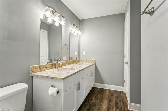 bathroom featuring baseboards, a sink, toilet, and wood finished floors