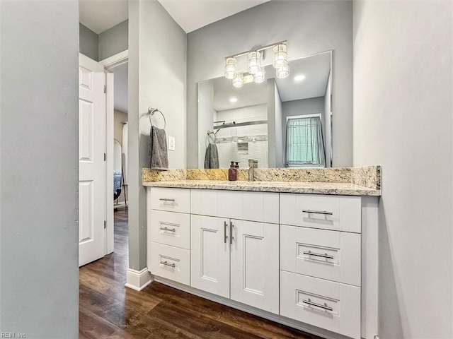 bathroom featuring a stall shower, connected bathroom, vanity, wood finished floors, and baseboards