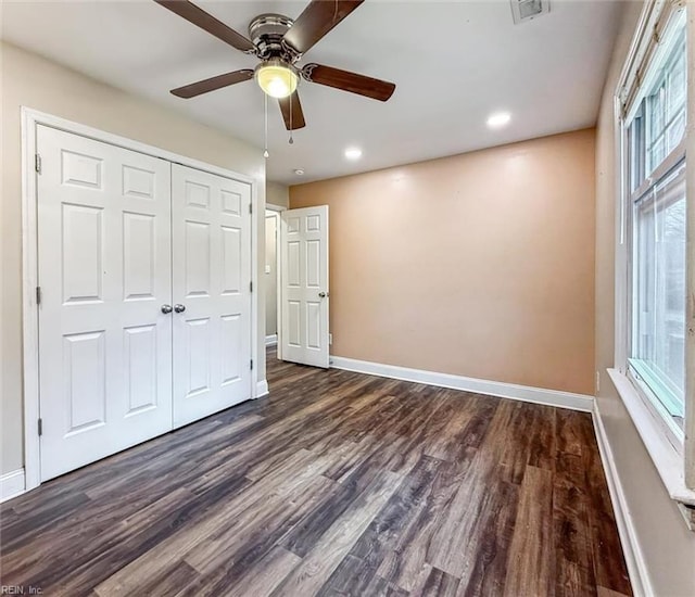 unfurnished bedroom featuring dark wood-type flooring, a closet, and baseboards