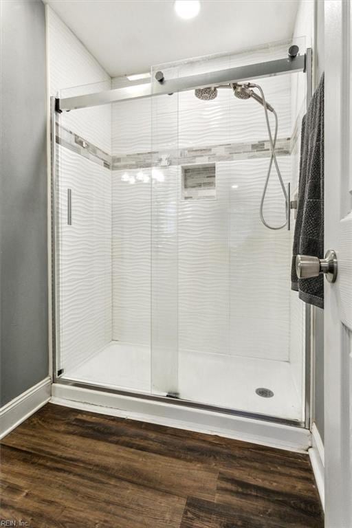 full bathroom featuring a stall shower, baseboards, and wood finished floors