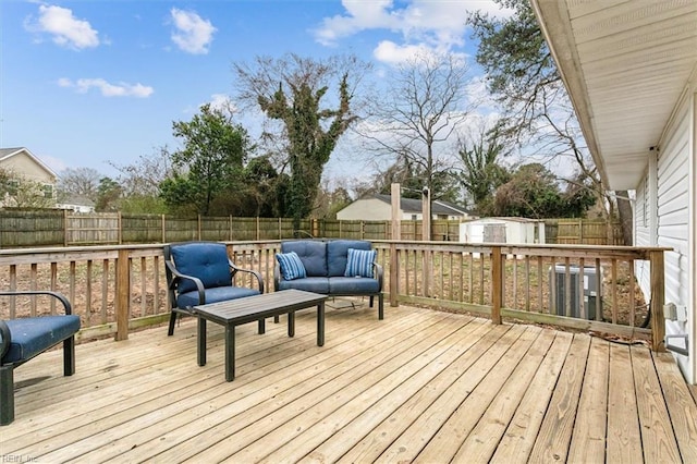 wooden deck featuring a storage shed, a fenced backyard, outdoor lounge area, and an outdoor structure