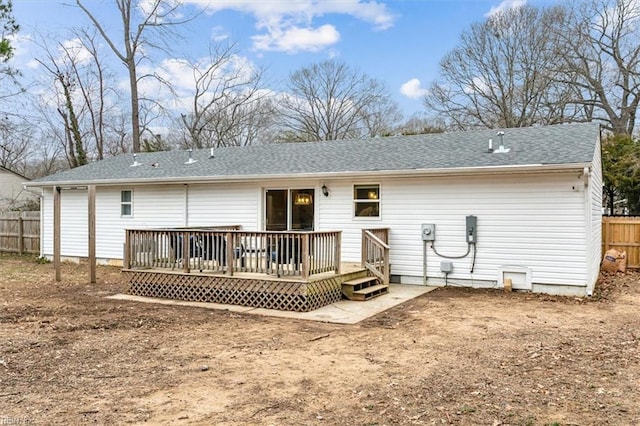 rear view of property featuring roof with shingles, fence, and a wooden deck