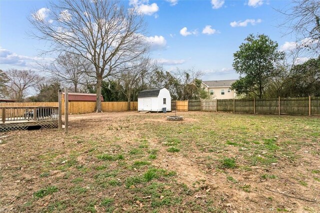 view of yard with a storage unit, an outdoor structure, a fenced backyard, and a wooden deck