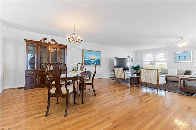 dining room featuring light wood finished floors, ceiling fan with notable chandelier, baseboards, and ornamental molding