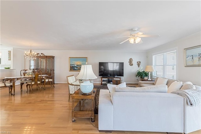 living room with ornamental molding, light wood finished floors, and ceiling fan with notable chandelier