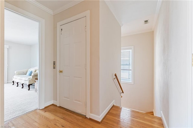 hall featuring visible vents, ornamental molding, an upstairs landing, and light wood-style floors