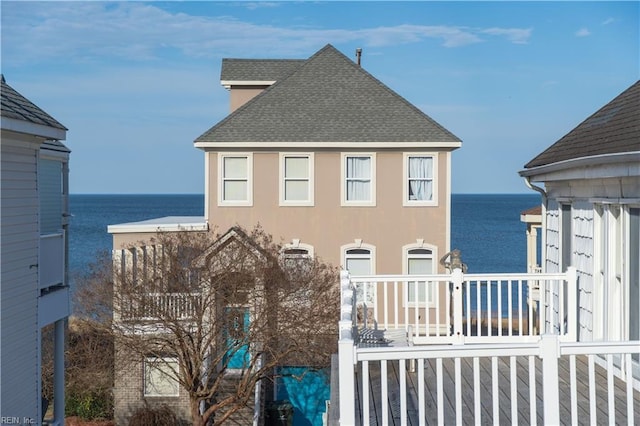 exterior space featuring a shingled roof, a water view, and stucco siding