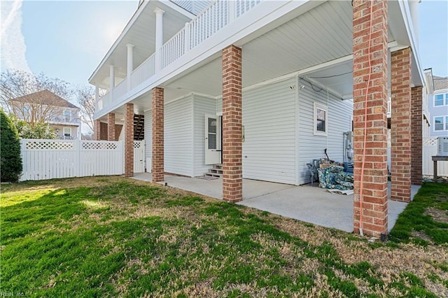 back of property featuring fence, a lawn, and a patio