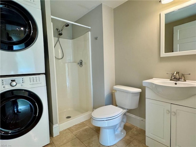 bathroom featuring tile patterned flooring, toilet, stacked washer / dryer, vanity, and a shower stall