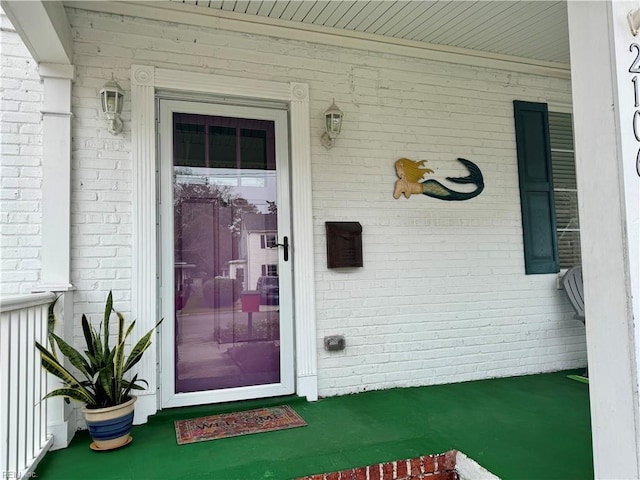 property entrance with a porch and brick siding