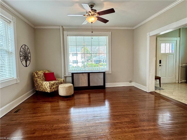 sitting room featuring plenty of natural light, ornamental molding, and wood finished floors