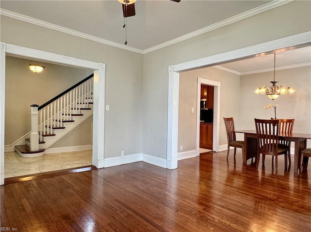 dining room featuring ceiling fan with notable chandelier, baseboards, stairs, ornamental molding, and hardwood / wood-style floors