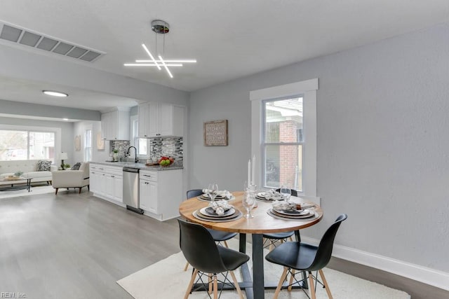 dining area featuring light wood-type flooring, plenty of natural light, baseboards, and visible vents