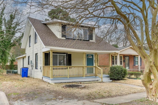 view of front of property featuring a shingled roof, covered porch, and brick siding