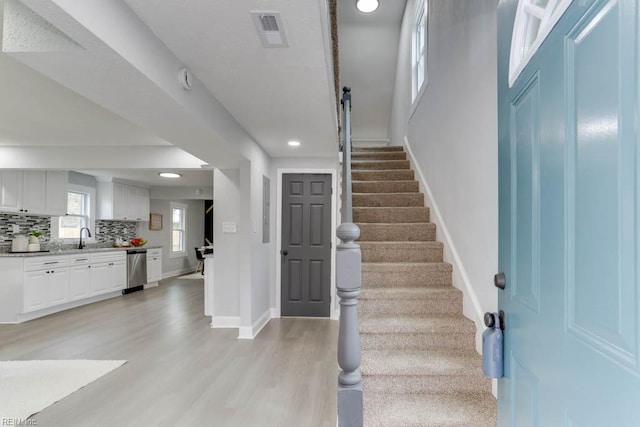 foyer entrance featuring recessed lighting, visible vents, light wood-type flooring, baseboards, and stairs