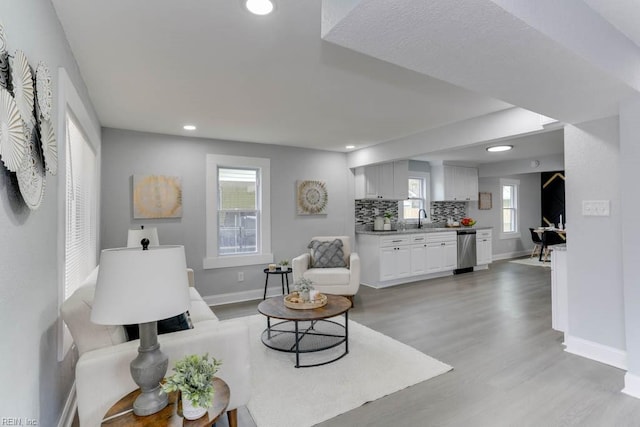 living area featuring light wood-style floors, baseboards, and recessed lighting