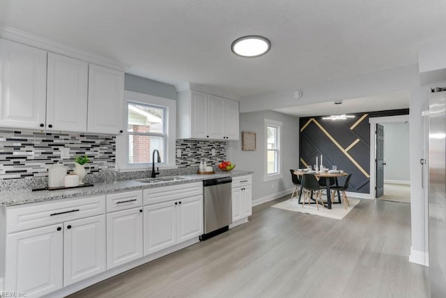 kitchen with a sink, white cabinetry, decorative backsplash, dishwasher, and light wood finished floors