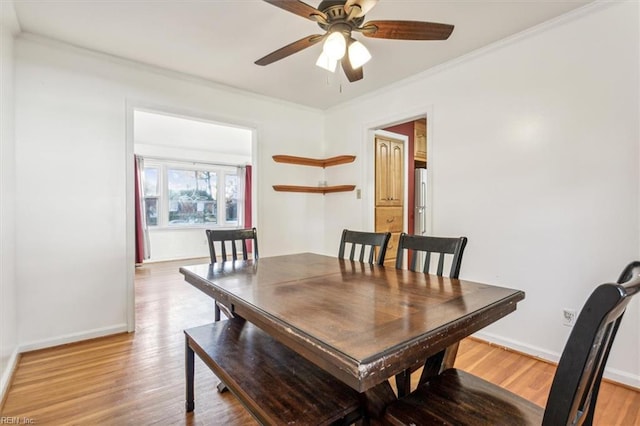 dining area featuring light wood-type flooring, ceiling fan, baseboards, and crown molding