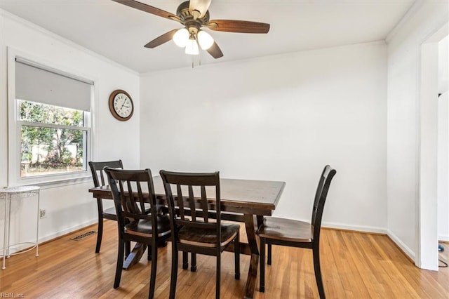 dining room featuring visible vents, baseboards, ceiling fan, ornamental molding, and light wood-style floors