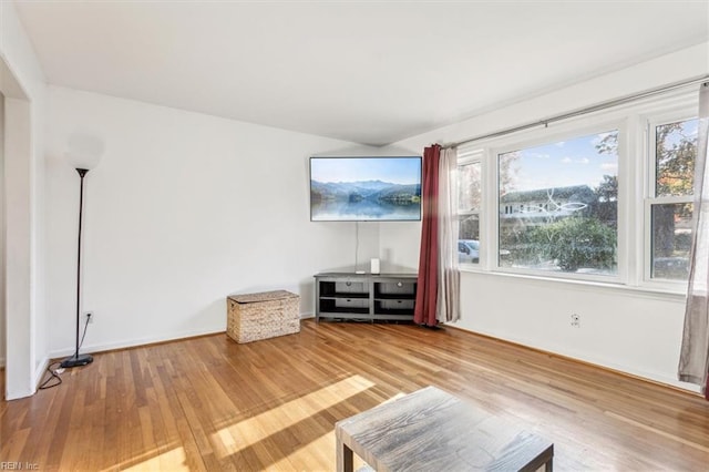 unfurnished living room with wood finished floors and baseboards