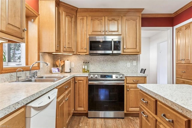 kitchen with appliances with stainless steel finishes, light countertops, a sink, and decorative backsplash