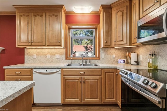 kitchen featuring appliances with stainless steel finishes, a sink, light countertops, crown molding, and backsplash