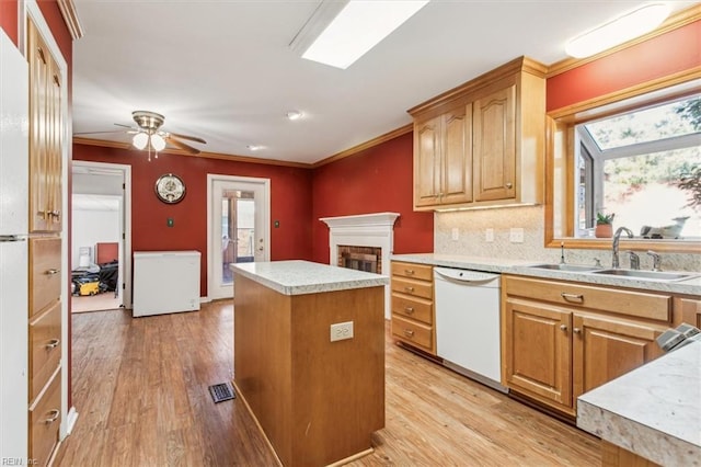 kitchen featuring refrigerator, a sink, a center island, dishwasher, and crown molding