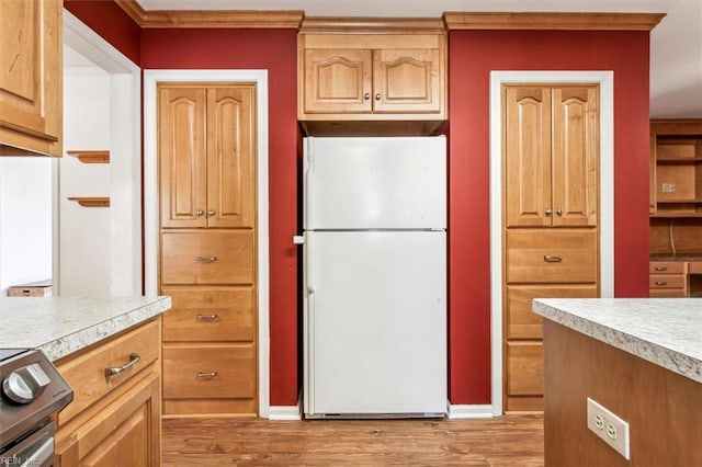 kitchen with light countertops, light wood-type flooring, freestanding refrigerator, and electric stove