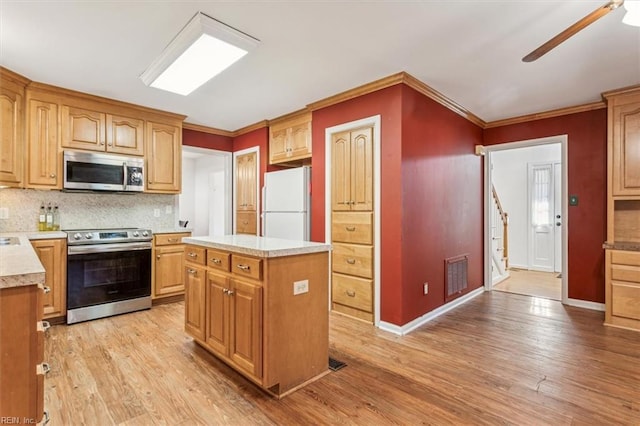 kitchen with stainless steel appliances, visible vents, light wood-type flooring, decorative backsplash, and crown molding