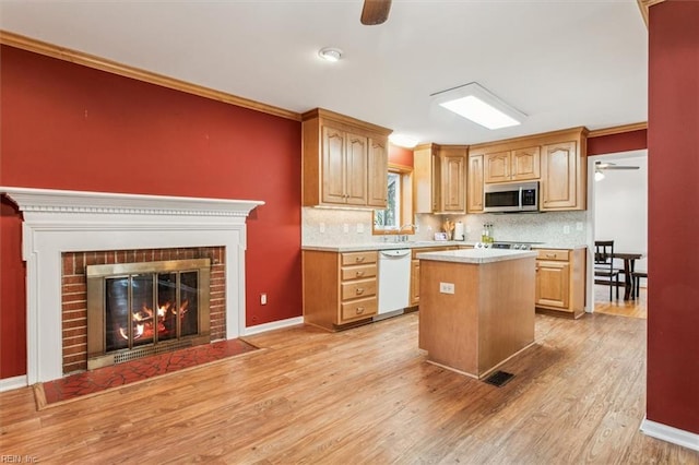 kitchen featuring a fireplace, light countertops, stainless steel microwave, ornamental molding, and dishwasher