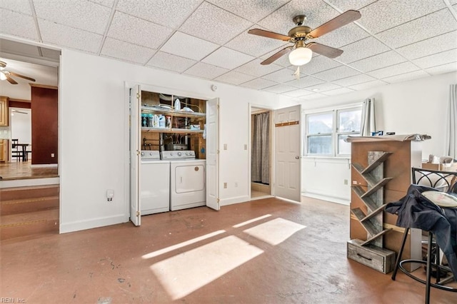 interior space with finished concrete flooring, a paneled ceiling, ceiling fan, independent washer and dryer, and baseboards