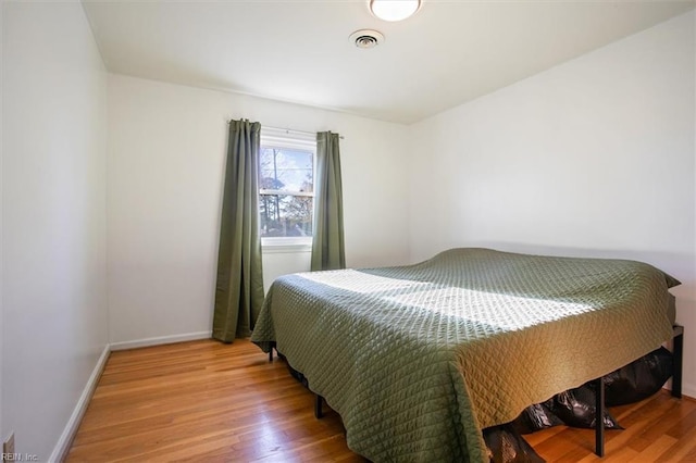 bedroom with visible vents, baseboards, and wood finished floors