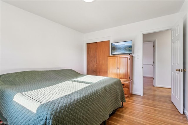 bedroom with a closet, light wood-style flooring, and baseboards