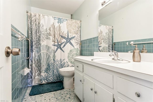 full bathroom with tile walls, toilet, wainscoting, vanity, and tile patterned flooring