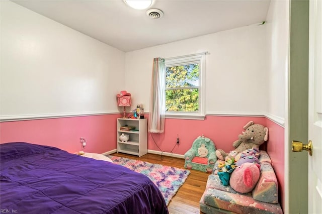 bedroom featuring baseboards, visible vents, and wood finished floors