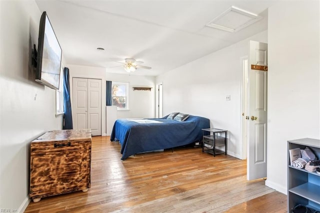 bedroom featuring light wood finished floors, a ceiling fan, attic access, and baseboards