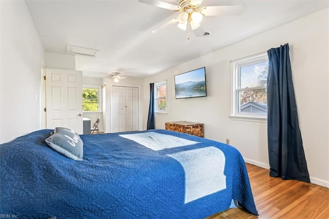 bedroom with attic access, baseboards, a ceiling fan, wood finished floors, and a closet